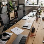 Spacious co-working office with wooden desks, laptops, and modern chairs.